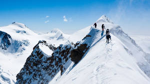 四位登山者在晴朗藍天下攀登積雪山脊。 — 運動 壁紙