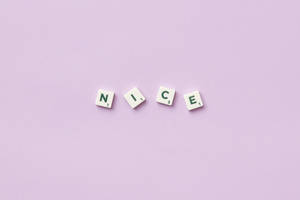 四個 Scrabble 字塊在紫色背景上拼出 nice