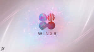 四個帶圖案的球體排列成標誌，下方有「WINGS」字樣。 — 粉紅色美學桌面 壁紙