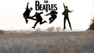 四個身穿黑色西裝的男人在草地上跳躍，上方有「The Beatles」字樣。 — 披頭四 壁紙