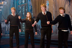 四名穿著霍格華茲制服的學生在一個大石廳中手持魔杖。 — MacBook Air M2 壁紙
