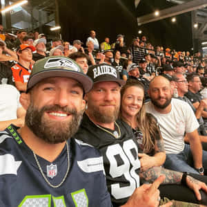 四名留鬍鬚的球迷身穿NFL球衣在體育館內微笑。 — 運動 壁紙
