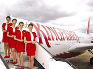 四名身穿紅色制服的航空公司員工在飛機樓梯上擺姿勢。 — 夢幻 GIF 壁紙