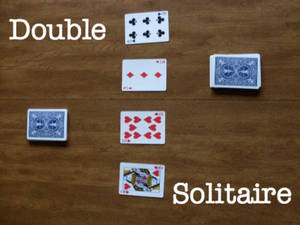四張撲克牌在木質表面上為接龍遊戲擺放，帶有「Double Solitaire」文字。 — 接龍 壁紙
