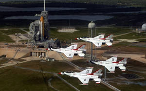 四架美國空軍雷鳥噴射機飛越NASA發射台，背景有火箭。 — 休士頓 壁紙