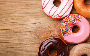 木桌上的四個彩色甜甜圈 — Dunkin Donuts 壁紙
