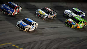 四輛NASCAR賽車在夜間賽道上緊密競速。 — F1 2019 壁紙