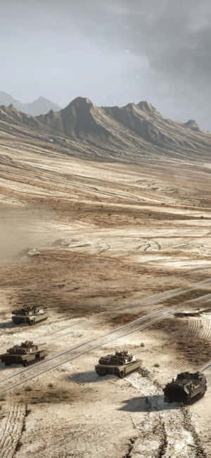 四輛軍用坦克在塵土飛揚的沙漠景觀中移動，背景是山脈。 — iPhone 15 壁紙