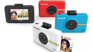 四部Polaroid Snap Touch即時相機，紅色、白色、藍色和黑色，附有樣本照片。 — Studio Display 壁紙
