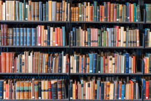 圖書館深色金屬書架上排列著色彩繽紛的復古書籍。 — 放大 壁紙