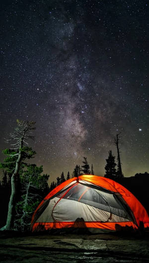 在繁星點點的夜空下，一個明亮的橙色帳篷，上方可見銀河。 — Pixel 4 壁紙