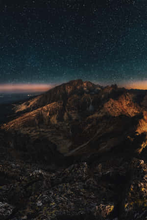 暮光中星光閃爍的山脈，山峰發光，天空黑暗。 — 山脈 壁紙