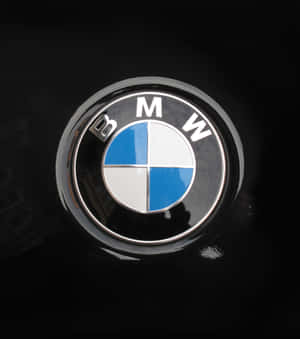 黑色汽車引擎蓋上的BMW標誌徽章，帶有鍍鉻飾邊和反射。 — 小米 Mix Flip 2 壁紙