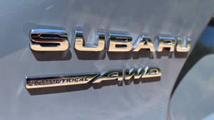 灰色引擎蓋上的鍍鉻 Subaru Symmetrical AWD 徽章