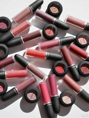 MAC化妝品唇彩和眼影以粉紅色和紅色調排列在白色背景上。 — 美學 Mac 壁紙