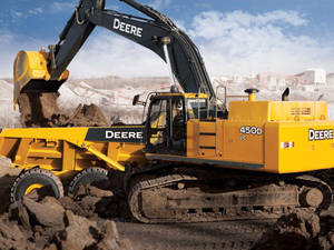 黃色 John Deere 挖土機在建築工地將泥土裝載到傾卸卡車上。