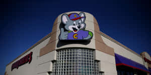 Chuck E Cheese's 吉祥物老鼠在建築物外牆豎起大拇指。 — 查克芝士 壁紙