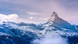 在寧靜的冬日景色中，雪山峰聳立於雲層之上。 — 山脈 壁紙