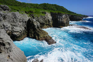 崎嶇的懸崖在清澈的藍天下與綠松石色的海洋波浪相遇。 — 關島 壁紙