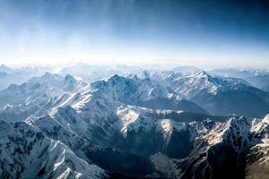 在清澈藍天下，白雪覆蓋的山峰延伸至遠方。 — 白雪公主 壁紙
