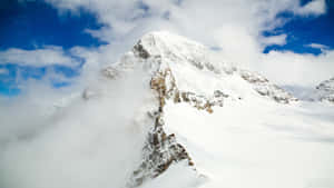 雪山頂峰聳立於雲層之上，藍天為背景 — 雪山 壁紙