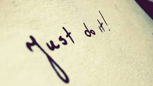 在紋理米色紙張上手寫的短語 just do it。 — 就去做吧 壁紙