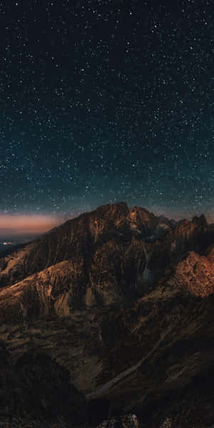 繁星點點的夜空在崎嶇的山峰之上，發光的地平線。 — 山脈 壁紙