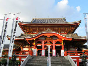 在多雲的天空下，擁有石階和傳統建築風格的紅色日本神社。 — 日式 壁紙
