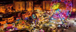 夜間燈火通明的遊樂園，色彩繽紛的遊樂設施和人群。 — 亞歷山卓 壁紙