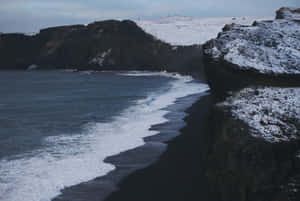 黑色沙灘，有積雪懸崖和拍岸浪花。 — 冰島 壁紙