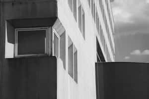 現代主義建築外牆，具有幾何窗戶和強烈陰影，在陰天天空下。 — 現代 壁紙