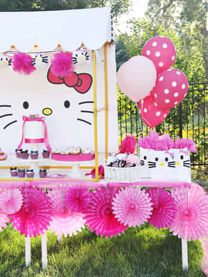 以Hello Kitty為主題的派對，在草地上擺放粉紅色裝飾和美食。 — Kindle Paperwhite 壁紙