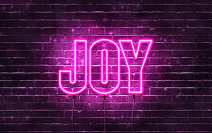 夜間潮濕磚牆上寫有 JOY 的粉紅色霓虹燈牌。 — 喜悅 壁紙