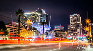 夜晚的城市街道，有發光的建築物和模糊的車燈。 — 鳳凰城太陽隊 壁紙