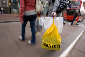 行人手持購物袋（包括一個黃色Forever 21袋）在城市人行道上行走。 — 永遠21 壁紙