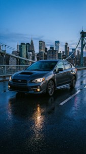 灰色Subaru WRX在濕橋上，黃昏時分城市燈光。 — 昴 壁紙