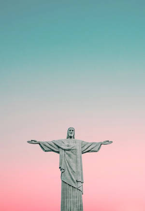 基督救世主雕像張開雙臂，背景為粉紅色和青綠色的天空。 — 耶穌手機 壁紙