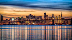 城市天際線與橋樑在日落時分，水面倒影。 — 天際線 壁紙