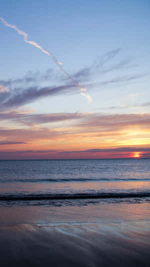 夕陽下的海洋，色彩繽紛的天空和濕沙 — 9:16 壁紙