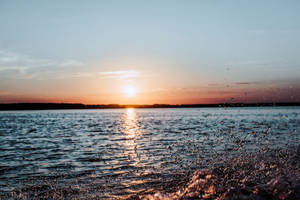 水面上的夕陽，前景的水花反射出金色的光芒。 — 海灘日落 壁紙