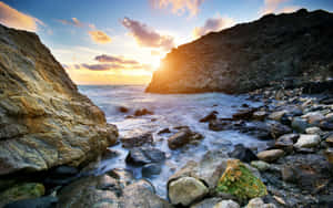 夕陽映照岩石海岸，海浪拍岸。 — 風景 壁紙