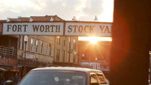 Fort Worth Stockyards上空的夕陽，前景有復古建築和一輛汽車。 — 沃斯堡 壁紙
