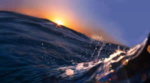 夕陽下的海浪，帶有發光的水滴和六角形光效。 — 日落 壁紙