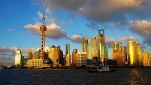 上海天際線在夕陽下，金色摩天大樓和江上船隻 — 唐人街 壁紙