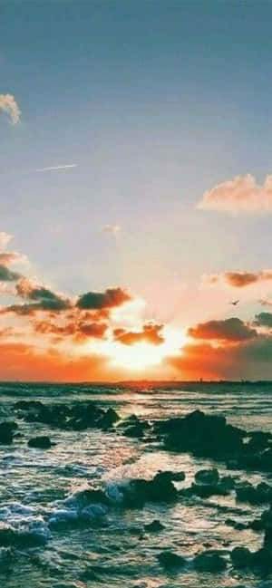 夕陽映照岩石海洋，色彩斑斕的雲朵和拍岸的浪花。 — 日落 壁紙