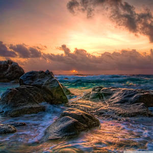 夕陽下的海洋，海浪拍打岩石 — 阿魯巴 壁紙