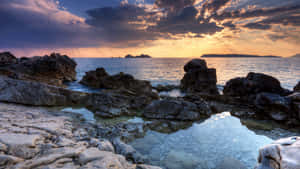 日落時分的海岸岩石，平靜的海面和戲劇性的天空 — 海洋桌面 壁紙