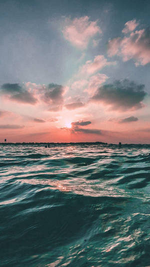 夕陽下的海洋，粉橙色天空和藍綠色海浪 — iPhone 6s Plus 壁紙