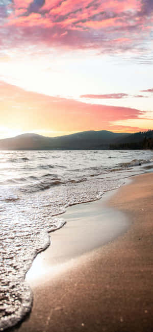 海洋上的夕陽，沙灘上的海浪，遠處的山巒 — 海灘 壁紙