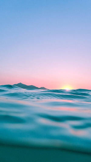 夕陽下的海浪，粉紅色和藍色的天空，遠山 — 海洋 壁紙